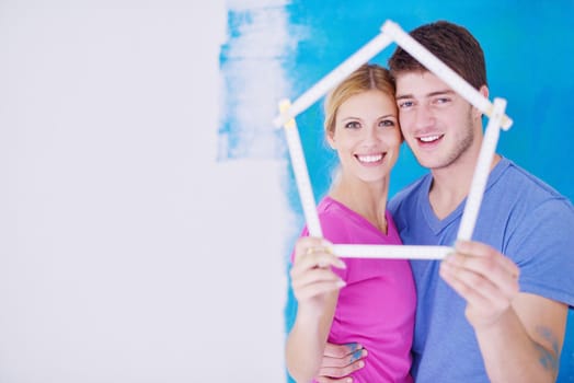 happy young couple paint in green and blue color white wall of their new home