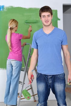 happy young couple paint in green and blue color white wall of their new home