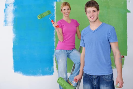 happy young couple paint in green and blue color white wall of their new home