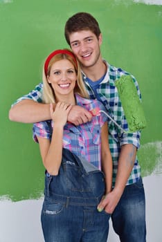 happy young couple paint in green and blue color white wall of their new home