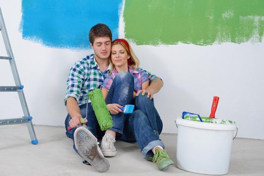 happy young couple relax after painting white wall in green and blue color in their new home