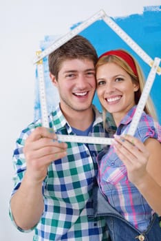 happy young couple paint in green and blue color white wall of their new home