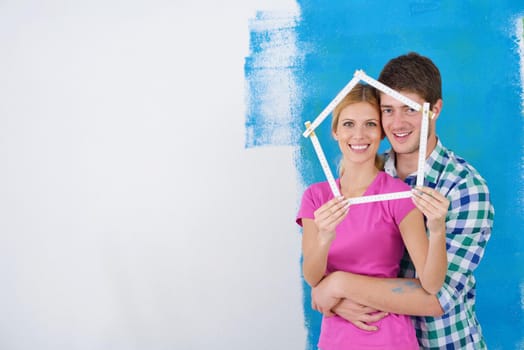 happy young couple paint in green and blue color white wall of their new home