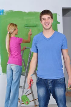 happy young couple paint in green and blue color white wall of their new home