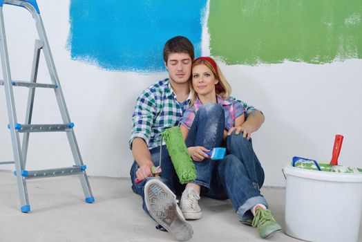 happy young couple relax after painting white wall in green and blue color in their new home