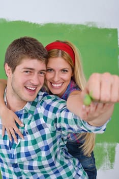 happy young couple paint in green and blue color white wall of their new home