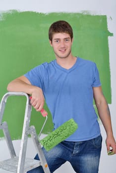 handsome young man paint in blue and green color  white wall of new home