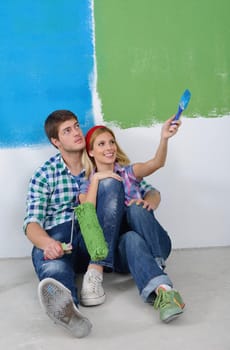 happy young couple paint in green and blue color white wall of their new home