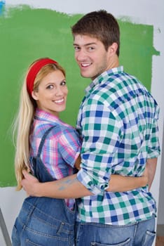 happy young couple paint in green and blue color white wall of their new home