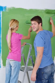 happy young couple paint in green and blue color white wall of their new home