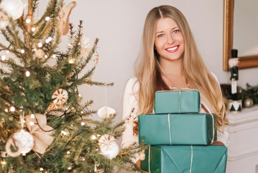 Christmas holiday and sustainable gifts concept. Happy smiling woman holding wrapped presents with eco-friendly green wrapping paper.