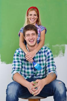 happy young couple paint in green and blue color white wall of their new home