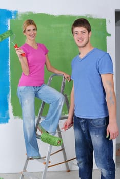 happy young couple paint in green and blue color white wall of their new home