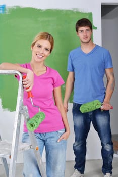 happy young couple paint in green and blue color white wall of their new home