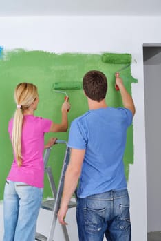 happy young couple paint in green and blue color white wall of their new home