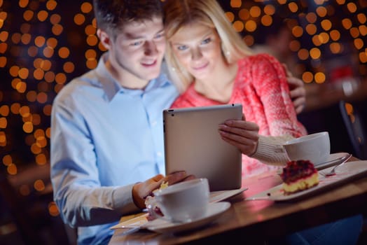 happy young couple with a tablet computer in restaurant