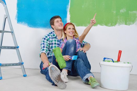 happy young couple relax after painting white wall in green and blue color in their new home