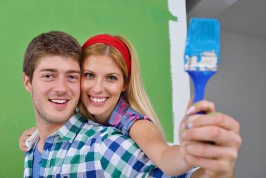 happy young couple paint in green and blue color white wall of their new home