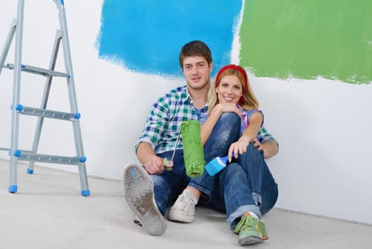 happy young couple paint in green and blue color white wall of their new home