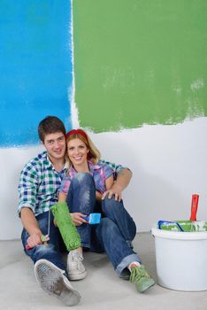 happy young couple relax after painting white wall in green and blue color in their new home