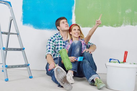 happy young couple relax after painting white wall in green and blue color in their new home