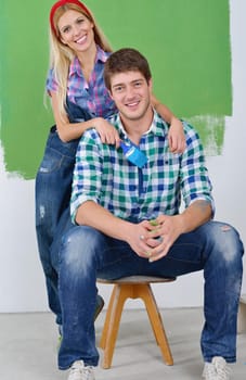 happy young couple paint in green and blue color white wall of their new home