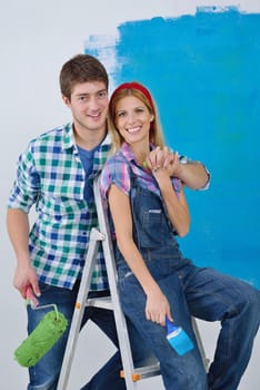 happy young couple paint in green and blue color white wall of their new home