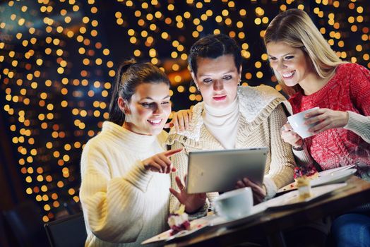 happy girls group  looking at a pc tablet in a home interior and have fun