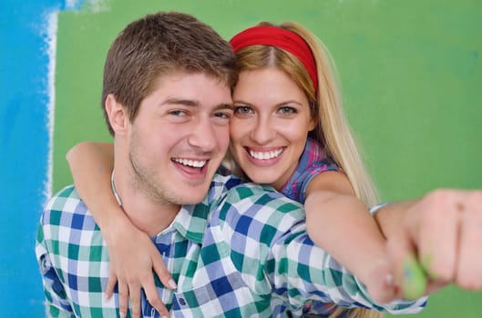 happy young couple paint in green and blue color white wall of their new home