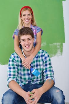 happy young couple paint in green and blue color white wall of their new home