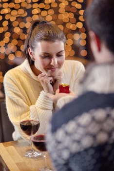 The young man gives a wedding ring   gift to  girl in restaurant