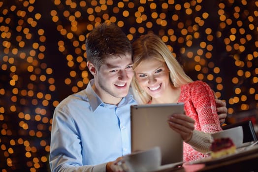 happy young couple with a tablet computer in restaurant