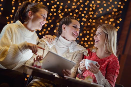 happy girls group  looking at a pc tablet in a home interior and have fun