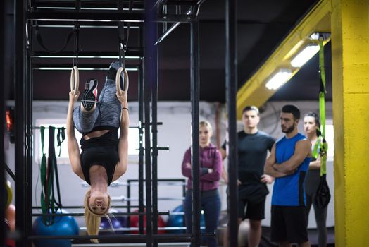 young athletic woman working out with personal trainer on gymnastic rings at the cross fitness gym