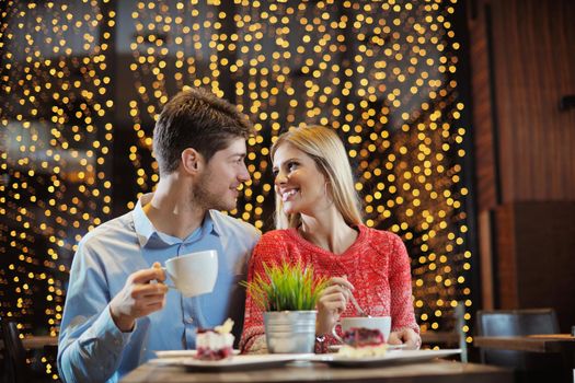 romantic evening date in restaurant  happy young couple with wine glass tea and cake