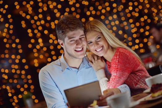 happy young couple with a tablet computer in restaurant