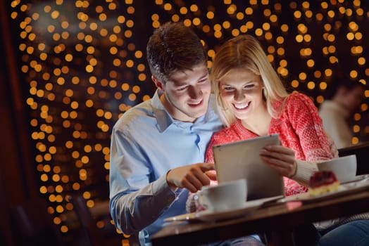 happy young couple with a tablet computer in restaurant