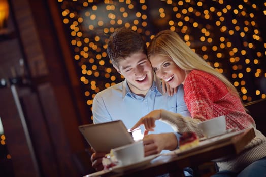 happy young couple with a tablet computer in restaurant