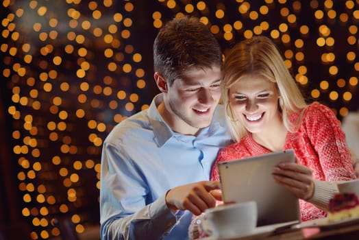 happy young couple with a tablet computer in restaurant