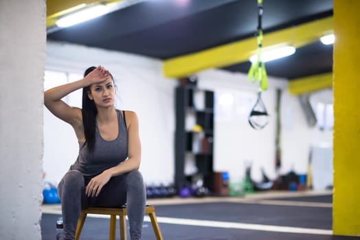 young athlete woman sitting and relaxing after exercise at cross fitness gym
