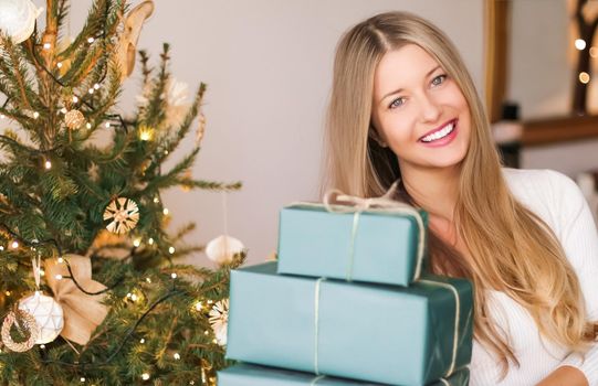 Christmas holiday and sustainable gifts concept. Happy smiling woman holding wrapped presents with eco-friendly green wrapping paper.