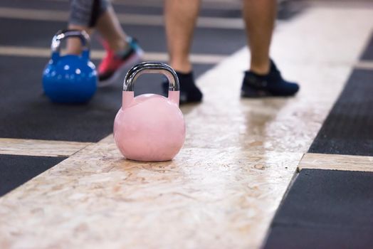 group of healthy young athletes doing exercises with kettlebells at cross fitness studio