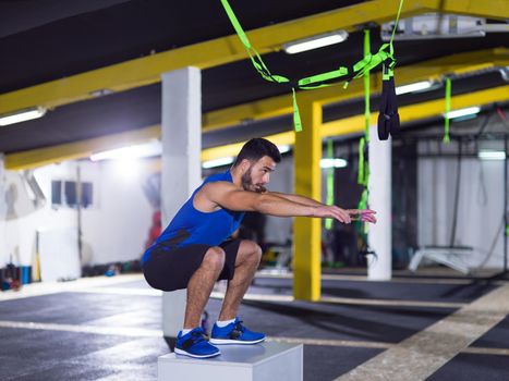 young athletic man training  jumping on fit box at crossfitness gym