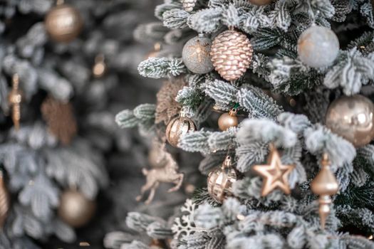 Close-up of a festively decorated outdoor Christmas tree with balls on a blurred sparkling fairy background. Defocused garland lights, bokeh effect