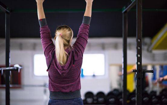 young muscular woman doing pull ups on the horizontal bar as part of Cross fitness Training