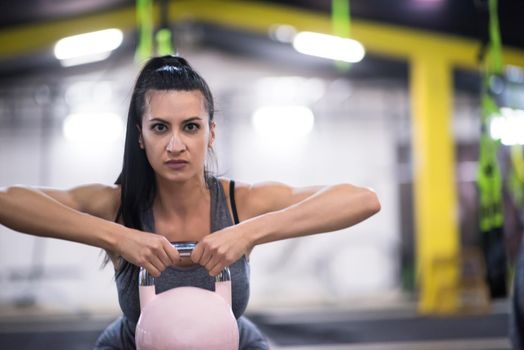 young  woman athlete exercise with fitness kettlebell at cross fitness gym