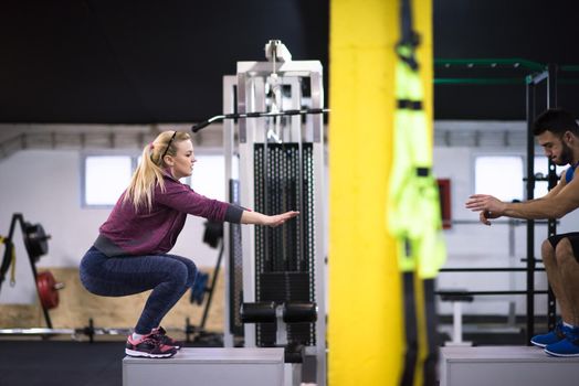 group of young healthy athletic people training jumping on fit box at cross fitness gym