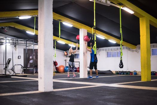 young athletes couple working out with medical ball at cross fitness gym