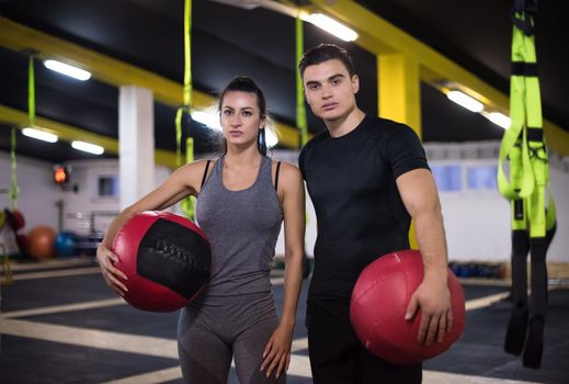 young athletes couple working out with medical ball at cross fitness gym