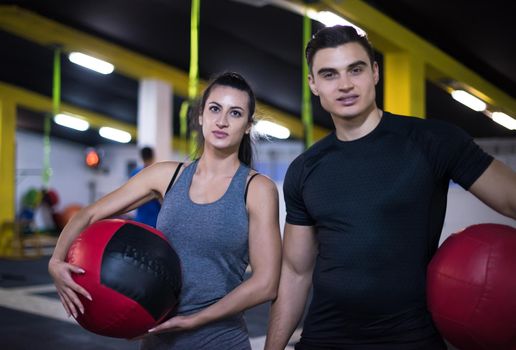 young athletes couple working out with medical ball at cross fitness gym